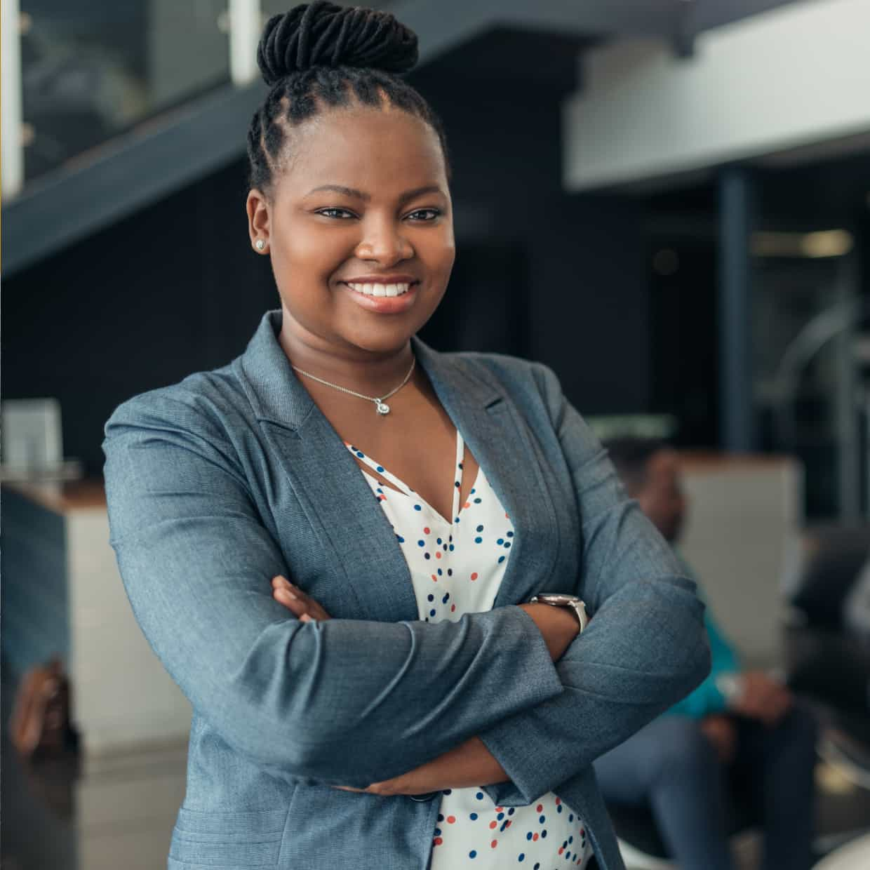 A confident woman with arms crossed in a modern office. 