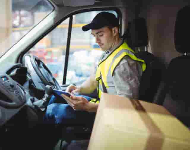 Delivery driver in van looking at phone