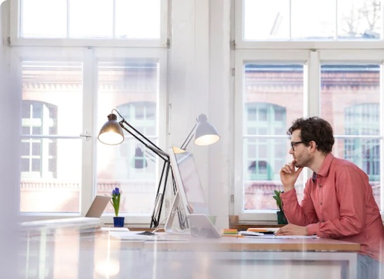 A man works at an iMac in a modern looking office.