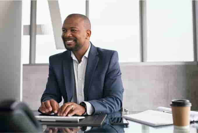 A smiling accountant sitting in an office typing on a keyboard while using QuickBooks Online Accountant.