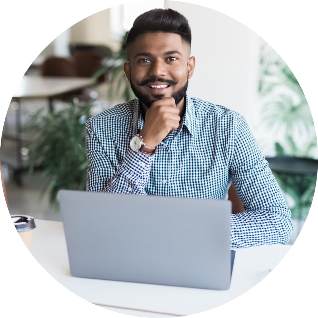 Accountant working on his laptop, smiling at viewer. 