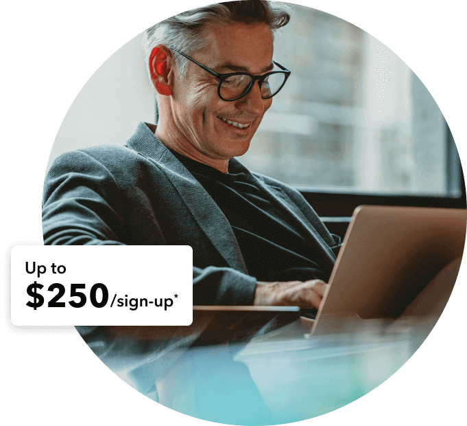 Man wearing blazer smiles while looking at laptop and seeing the up to $250/sign-up reward. 