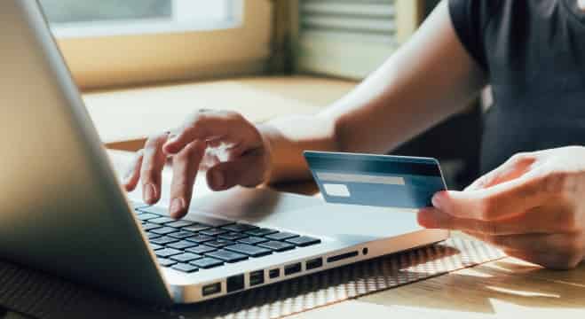 Une femme tenant sa carte de crédit devant son portable pour faire un paiement en ligne