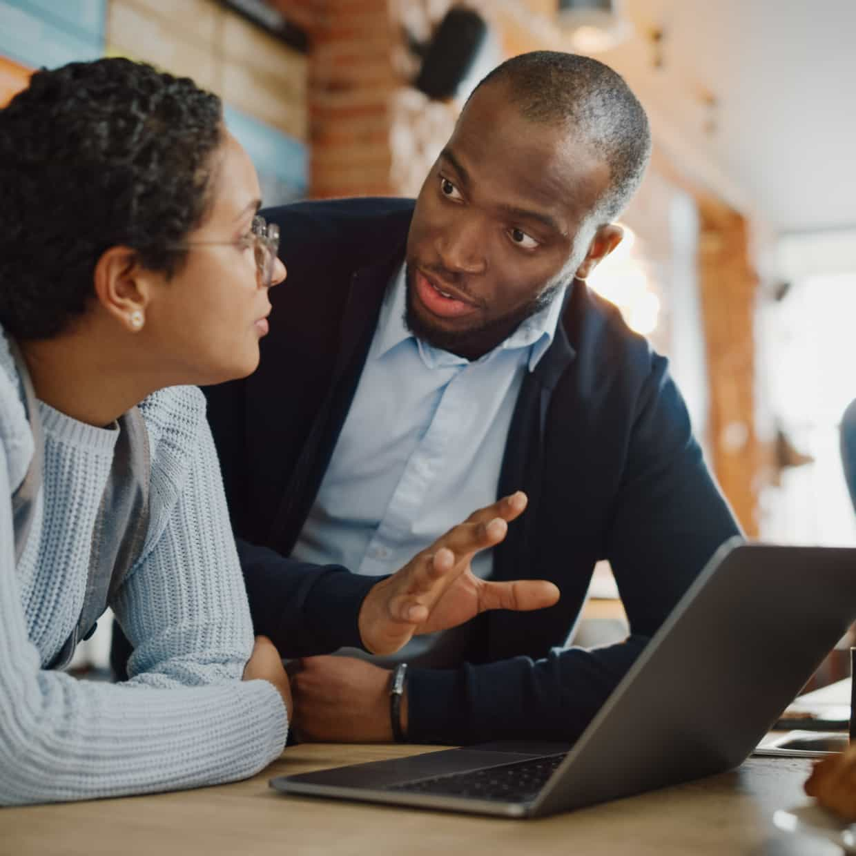 A man and woman consult over a laptop.