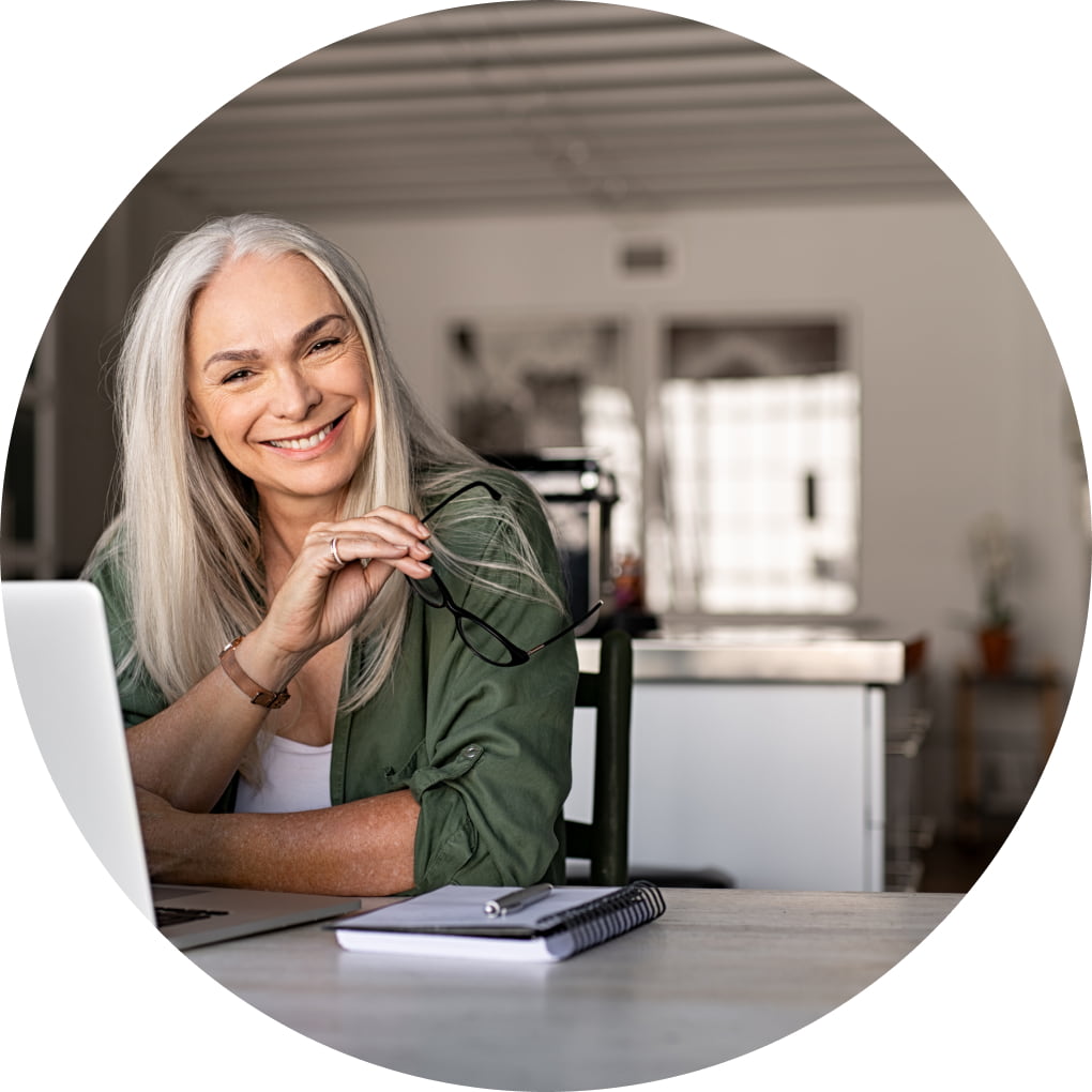 Accountant working from home on her laptop, holding a pair of glasses. 