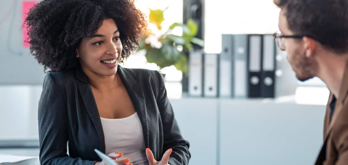 A smiling accountant, wearing a dark green blazer, happily engages with a client.