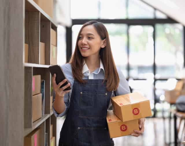 Woman checking inventory with packed boxes in hand