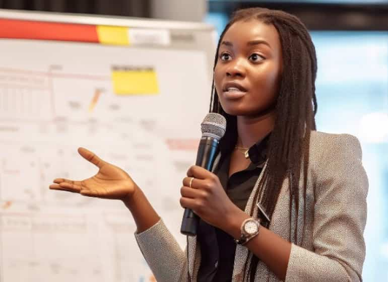 A woman giving a presentation, holding a microphone.