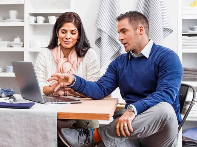 A person and person sitting at a desk with a laptop.