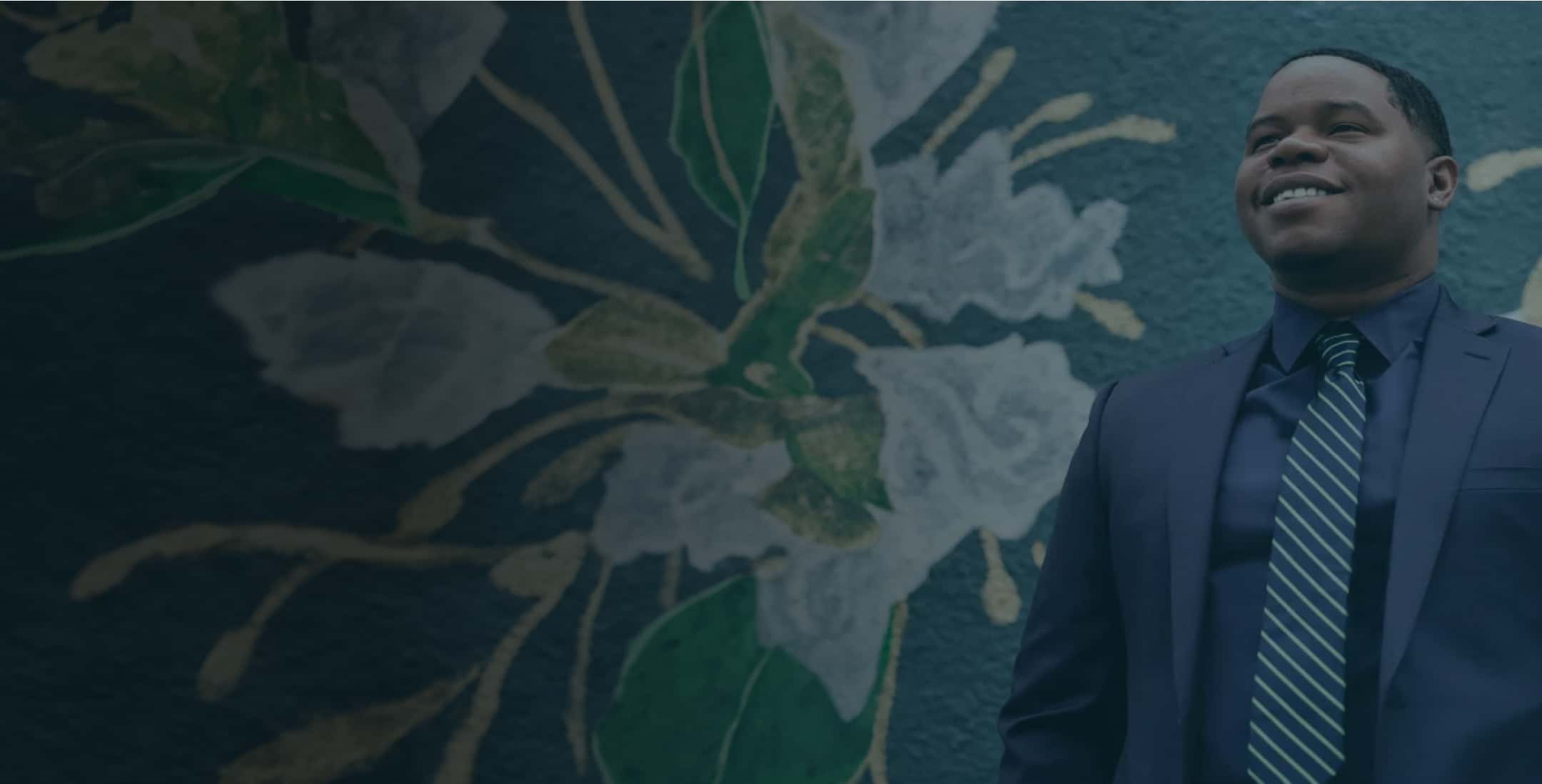 A person in a suit and tie standing in front of a wall.