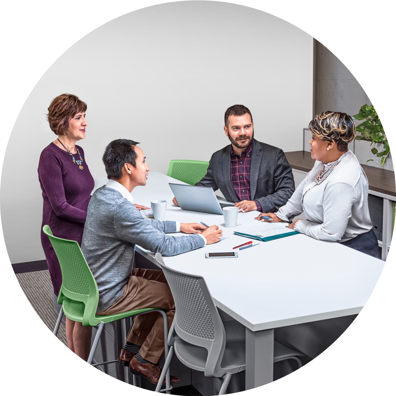 A group of people sitting at a table with laptops.