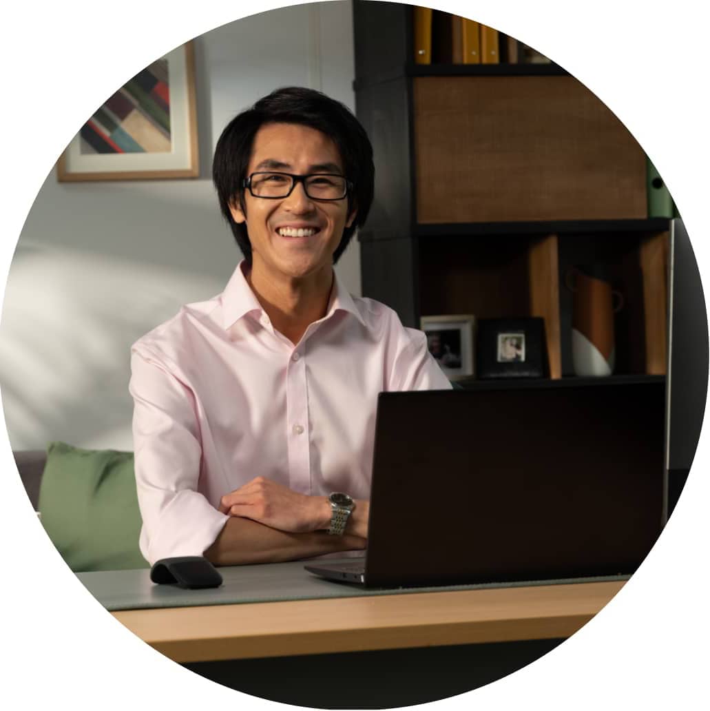 A smiling person with glasses on a computer.