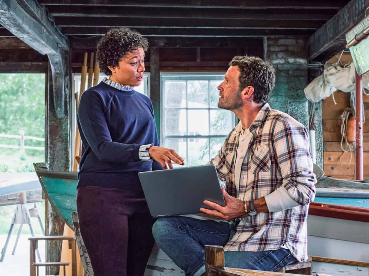 A person and person sitting on a couch with a laptop.