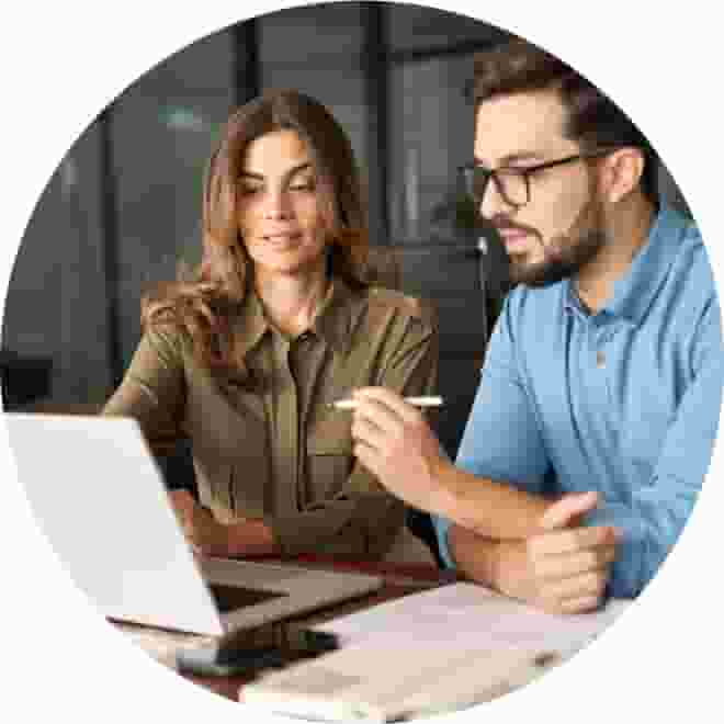 A person and person sitting at a table with a laptop.