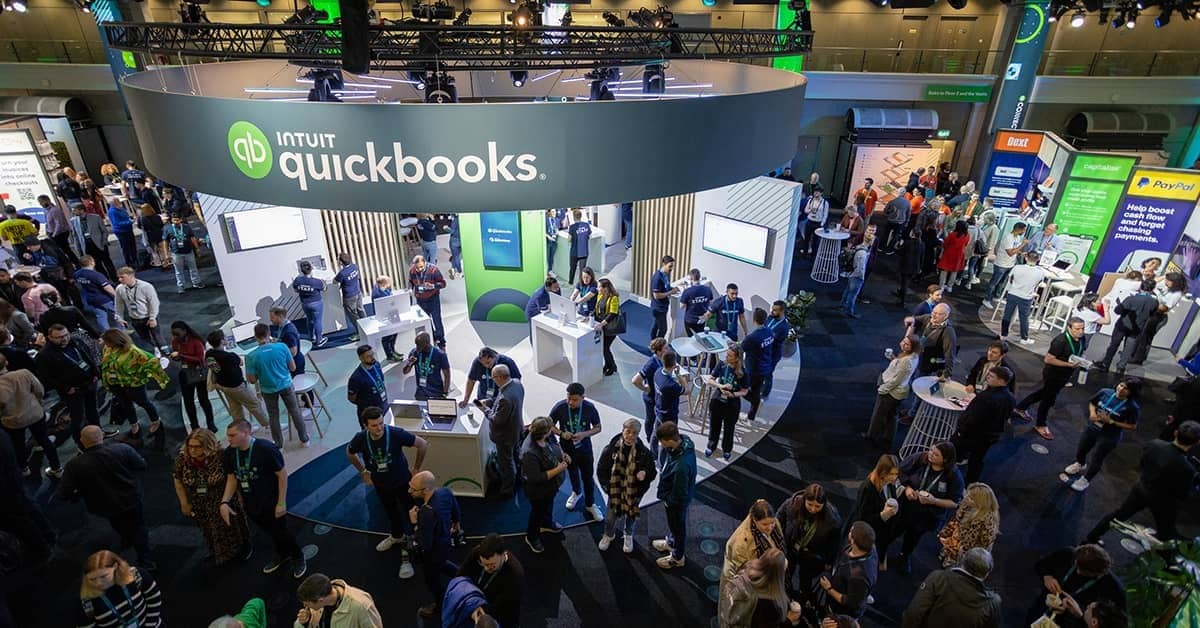 A group of people standing around a room with laptops.