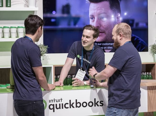 A group of people standing around a table with laptops.