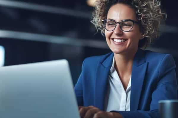 A person is smiling while holding a laptop.