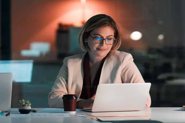 A person sitting at a desk with a laptop and a cup of coffee.