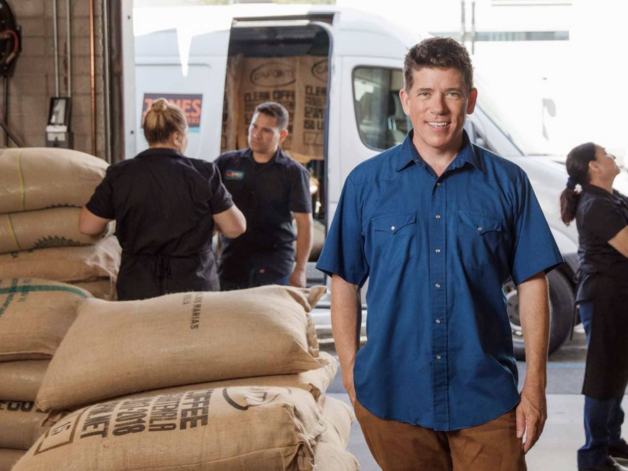 A person standing in front of a truck with a bag of coffee.