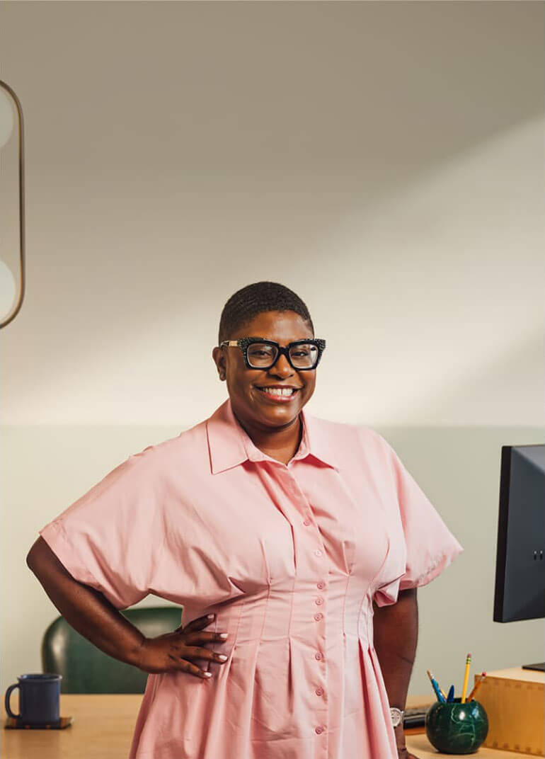 A smiling person in glasses and a pink shirt.