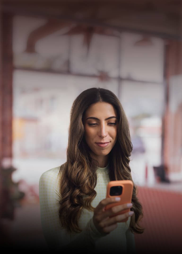 A person sitting down looking at her cell phone.