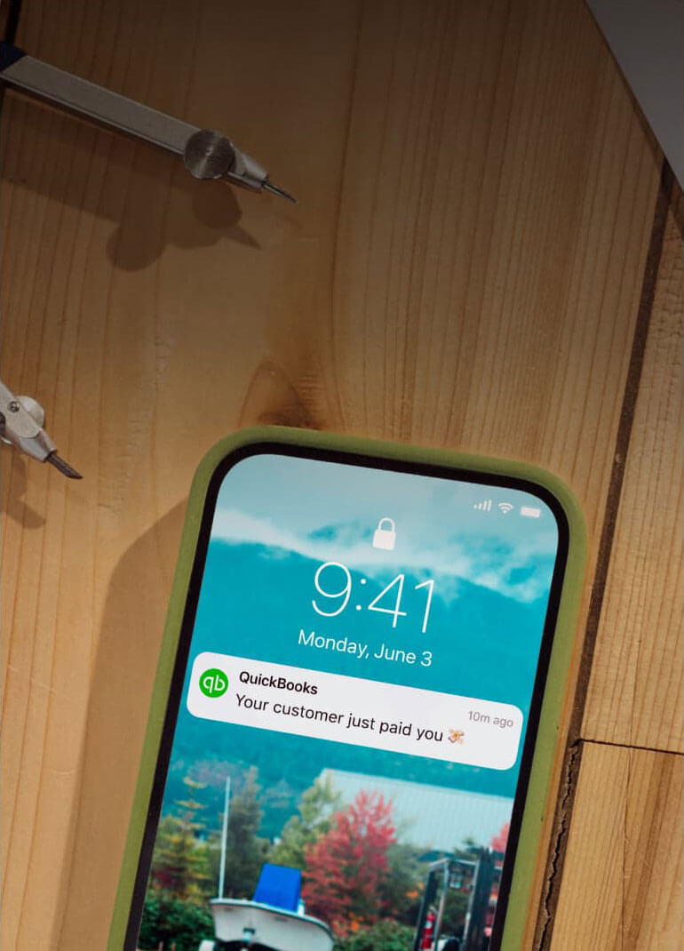 A phone with a notification from QuickBooks.
