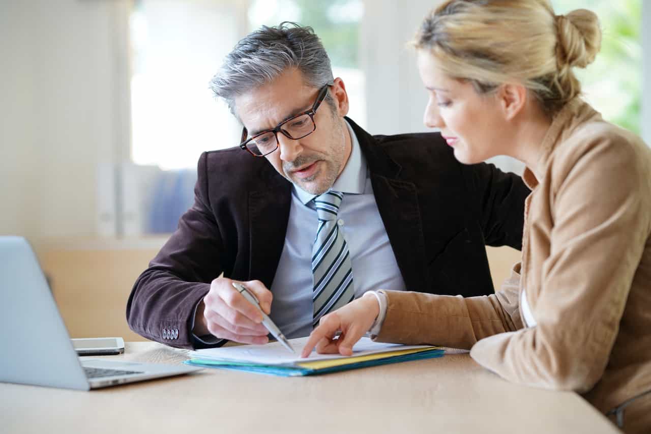 A person and person sitting at a table with a laptop.