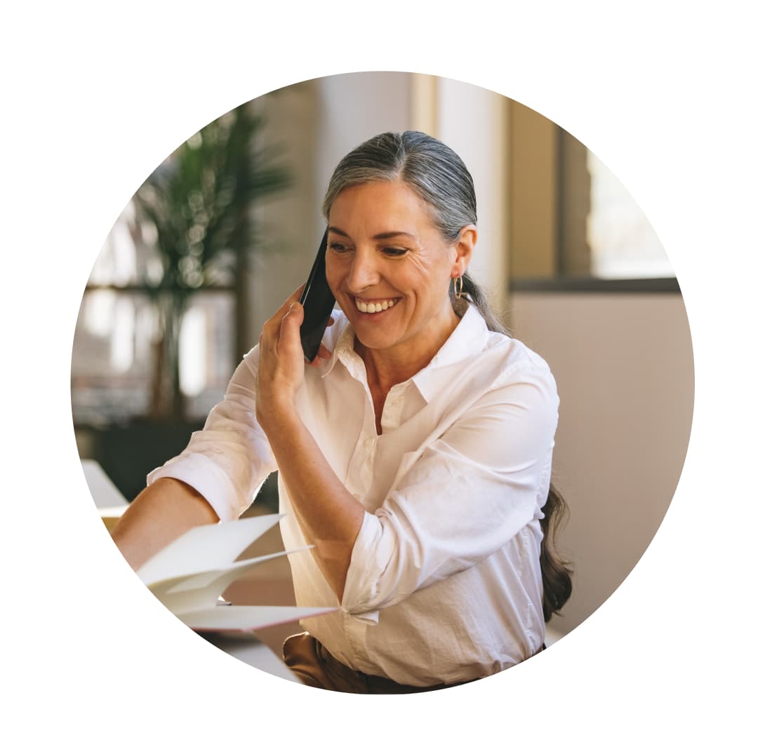 A person sitting at a table talking on a cell phone.