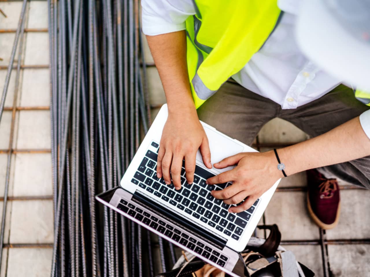 Close up details of engineer working on laptop on construction site.