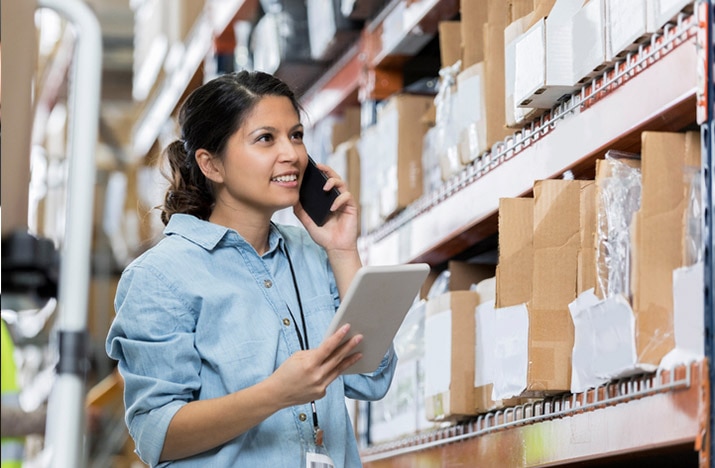 Manager on phone while checking inventory levels on QuickBooks inventory management software.