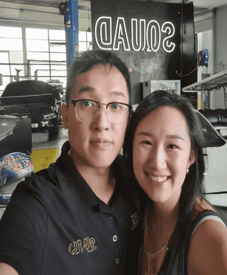 Two people posing in automotive workshop setting