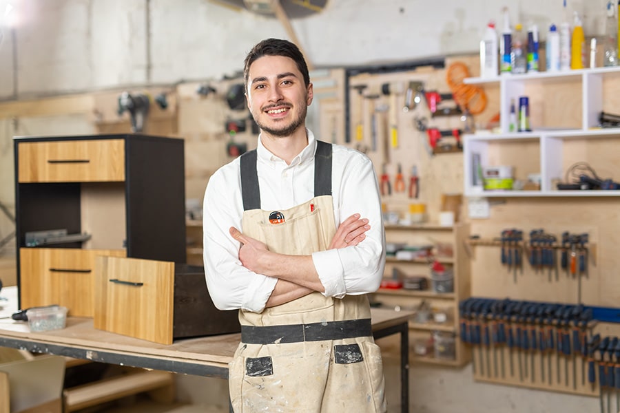 Un emprendedor sonríendo en su taller de producción de muebles