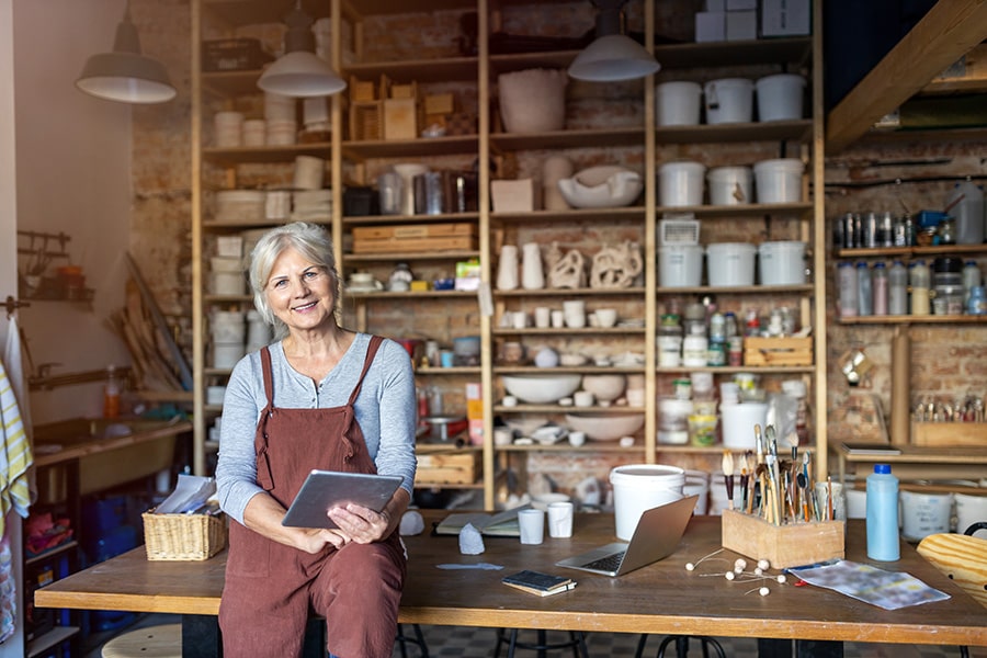 Emprendedora sentada en una mesa de su taller de arte revisando las cuentas de su pyme