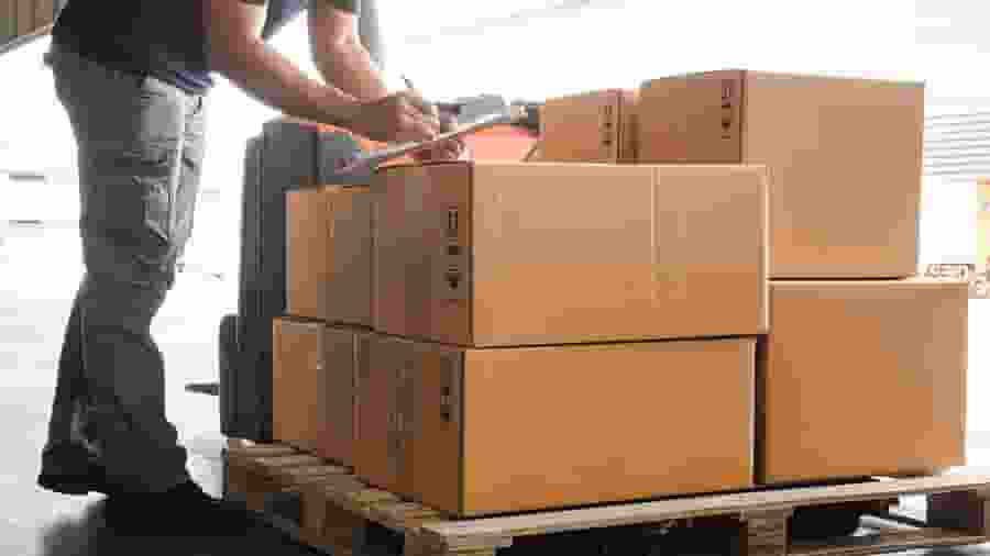 Man checking off inventory on pallet in warehouse