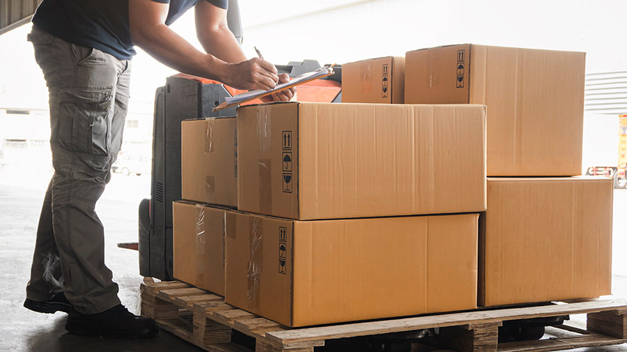 Man checking off inventory on pallet in warehouse