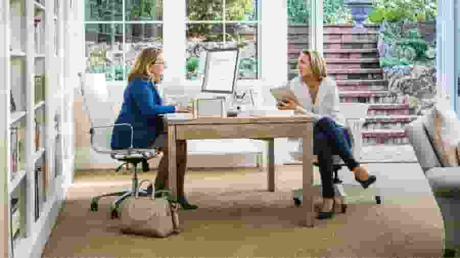 Two people sitting at a table with laptops.