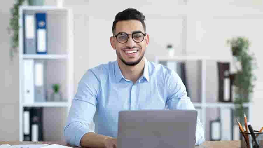 A person in a blue shirt working on a laptop.