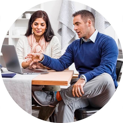 A person and person sitting at a table with a laptop.