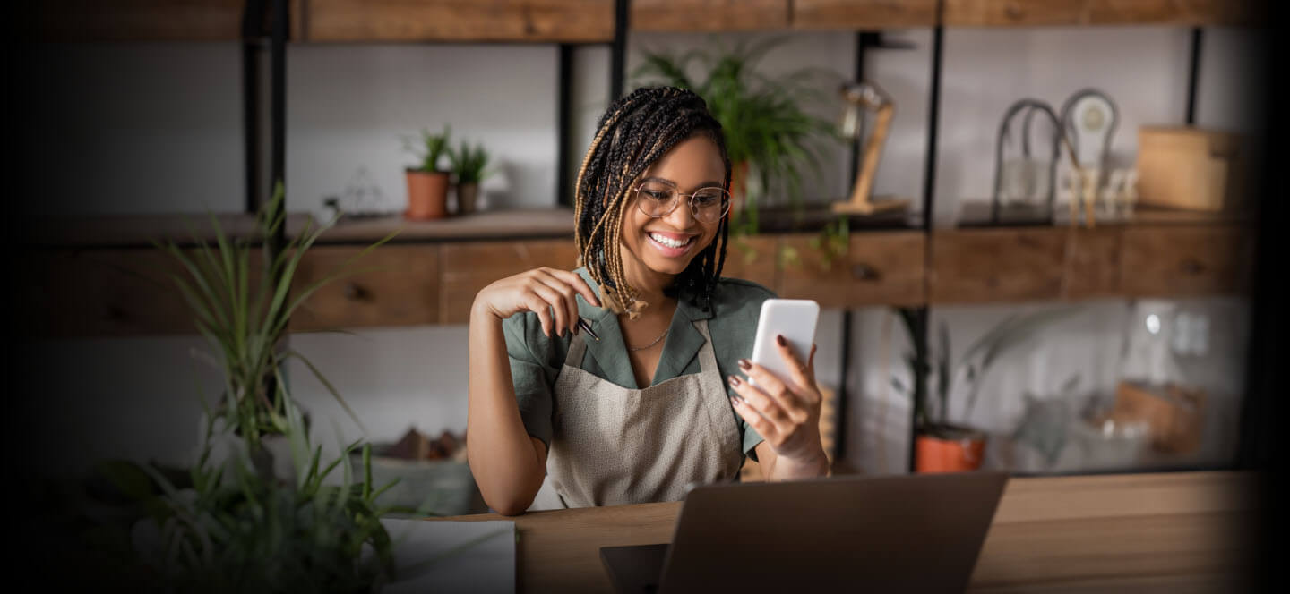 A person sitting at a table with a laptop and a cell phone.