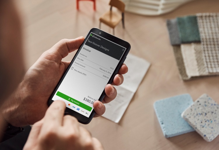 Man paying invoice on QuickBooks using mobile device