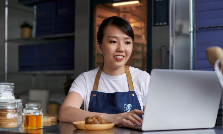 A small business owner is accessing QuickBooks financial reporting software on her laptop for business insights