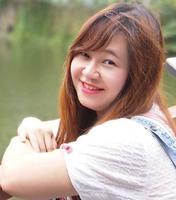 A person sitting on a bench smiling while holding a flower.