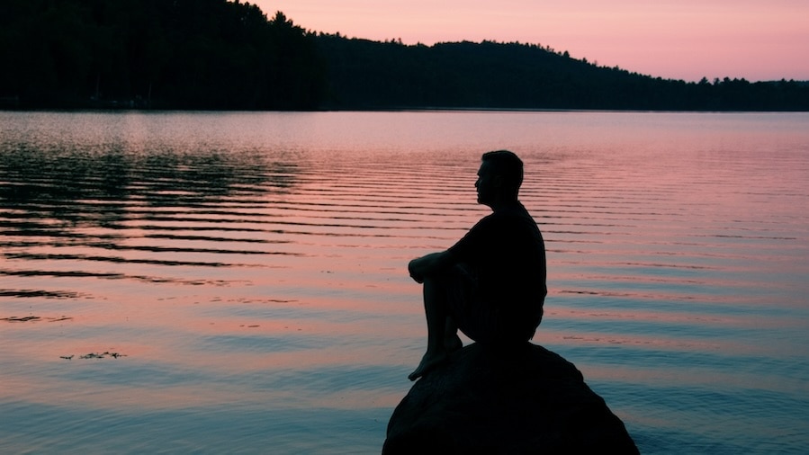 A man meditating by the lake.