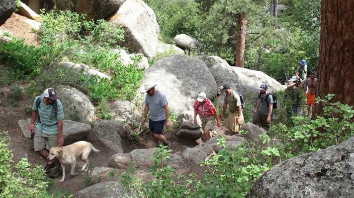 A group of people walking with some animals.
