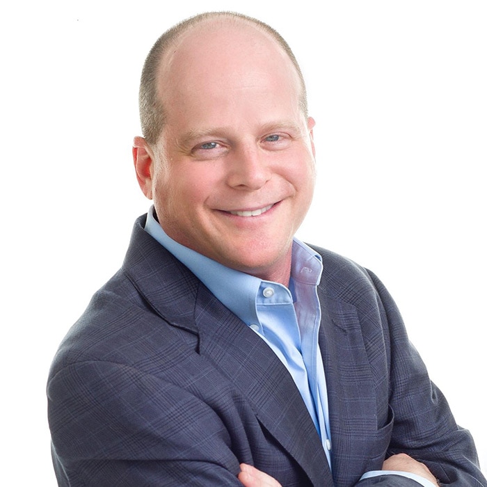 A person in a suit and tie smiles.