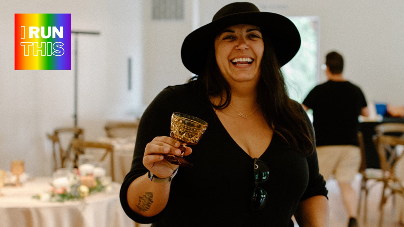 A person holding a glass of wine and a hat.