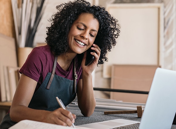 Small business owner on mobile phone in front of laptop