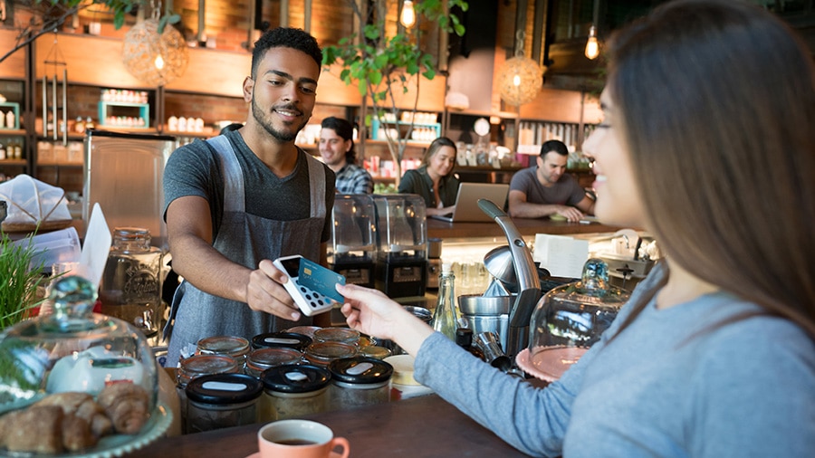 Photograph of a small business owner demonstrating how to accept credit card payments from a customer.
