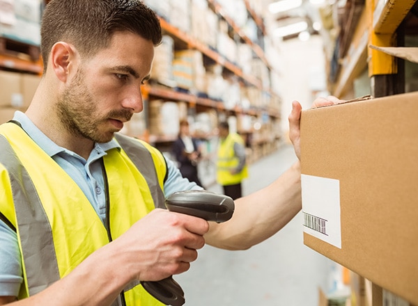 Man in warehouse using a barcode scanner to read SKU on box.