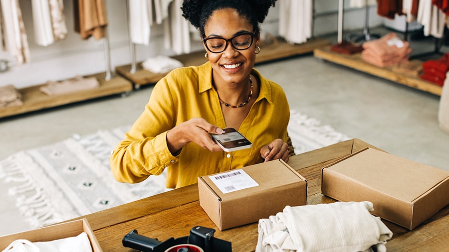 Small business owner using her phone to scan a barcode and track barcode inventory.